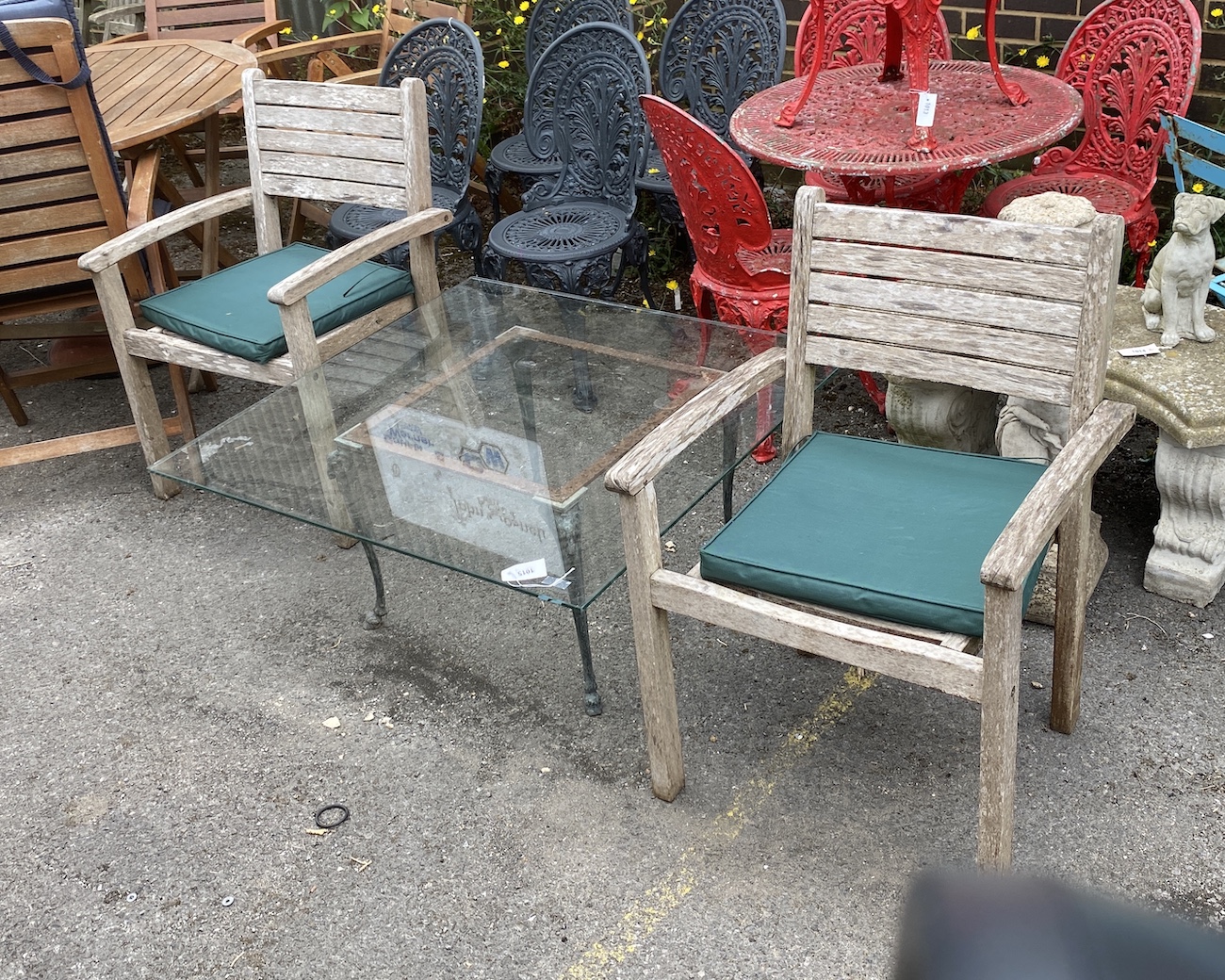 A square glass top cast metal garden table on a metal base, length 100cm, height 44cm together with a pair of teak elbow chairs